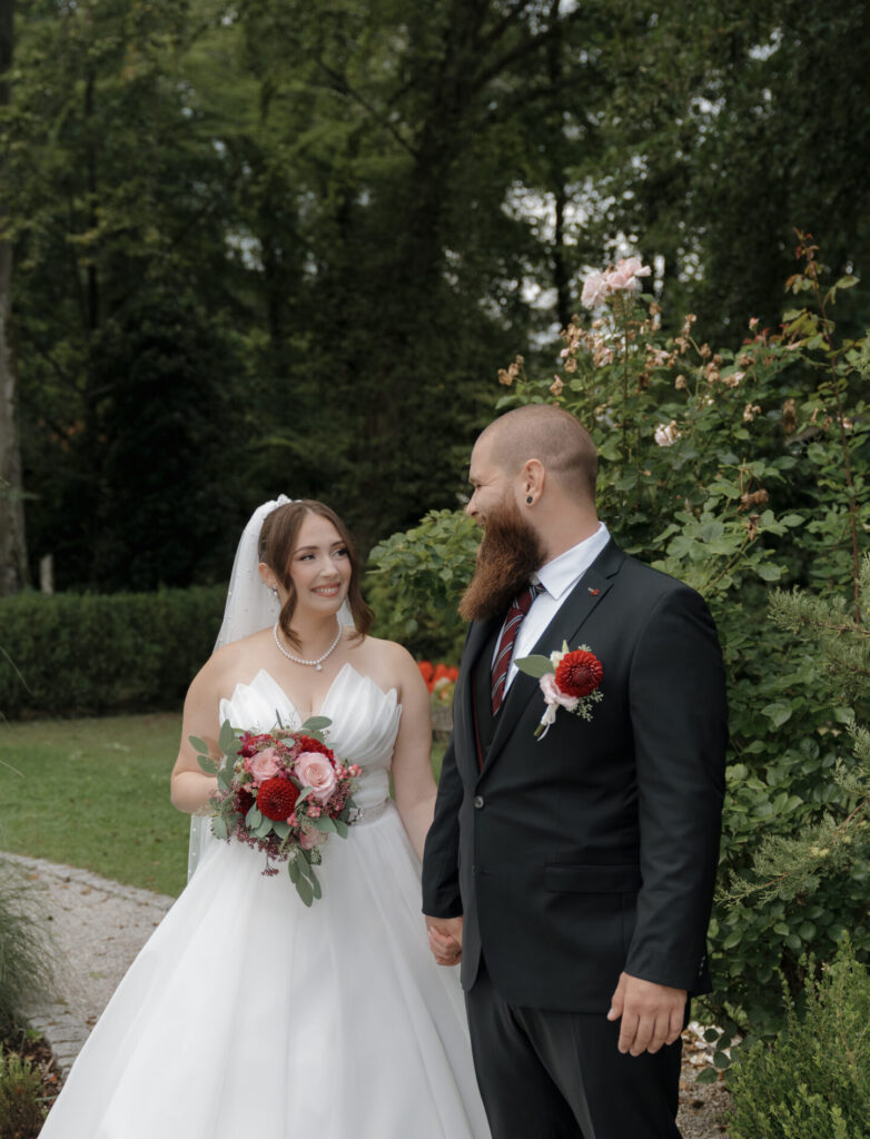 Emotionaler First Look des Brautpaares, sie lächeln sich liebevoll an, während der Bräutigam den Brautstrauß hält – authentische Hochzeitsfotografie