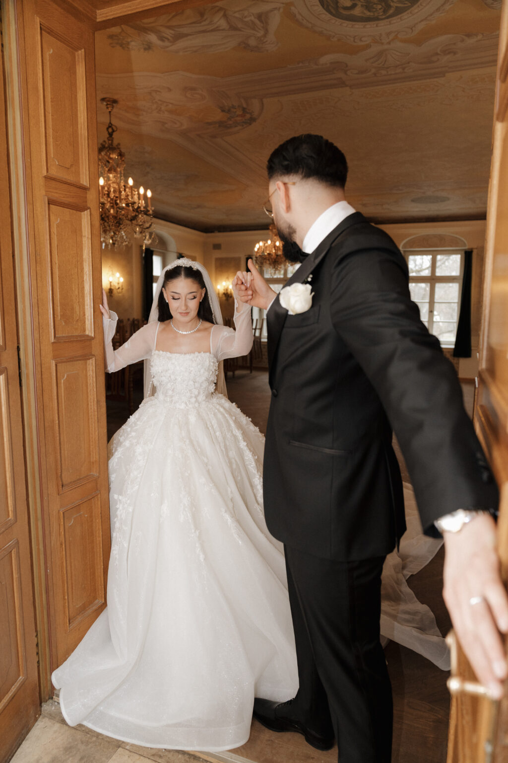 Brautpaar beim romantischen Moment. Bräutigam hält der Braut die Hand, öffnet die Tür und blickt sie liebevoll an